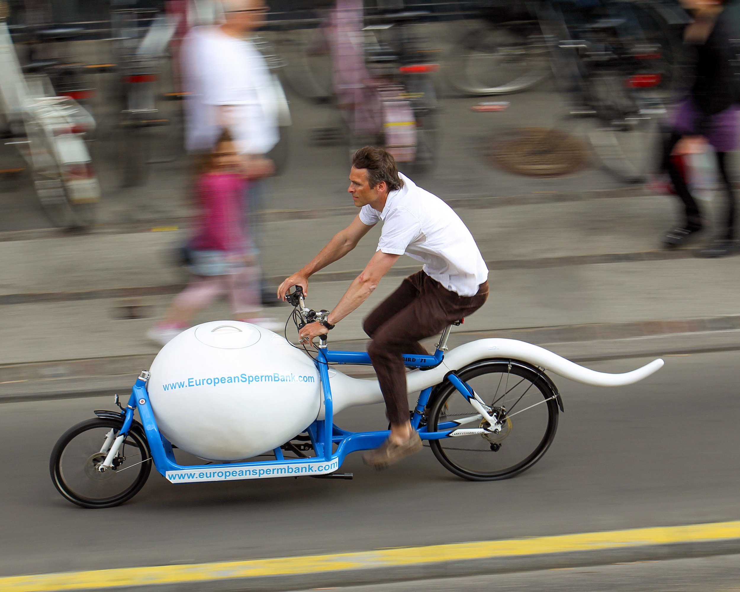 courier on a sperm shaped bicycle speeding down the road