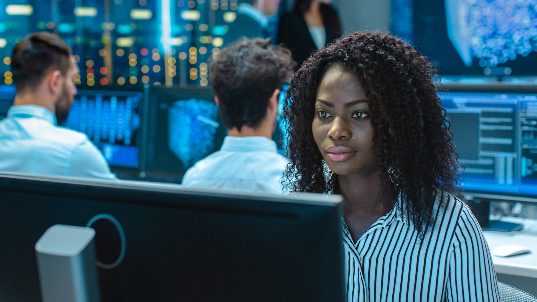 A stock image of a woman working at a computer in a data lab.