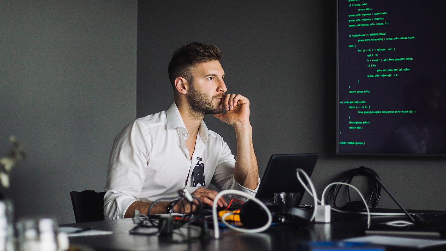 stock image of a man at his desk staring off, deep in thought