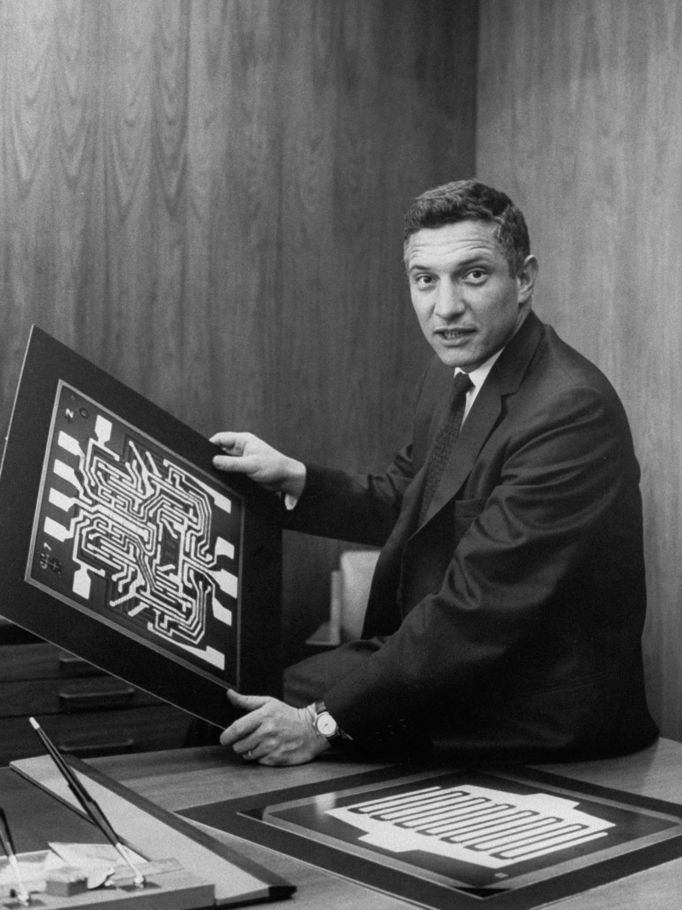 Robert Noyce in his office at Fairchild Semiconductor holding diagrams of semiconductors.